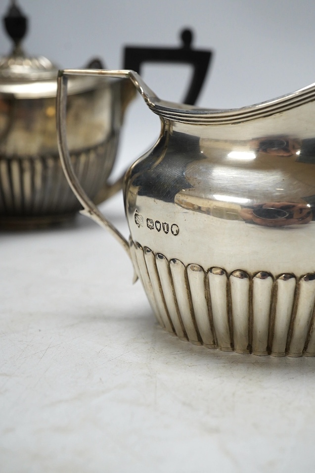 A matched late 19th/early 20th century demi-fluted silver three piece tea set, London, 1884 and later, gross weight 15.5oz. Condition - poor to fair